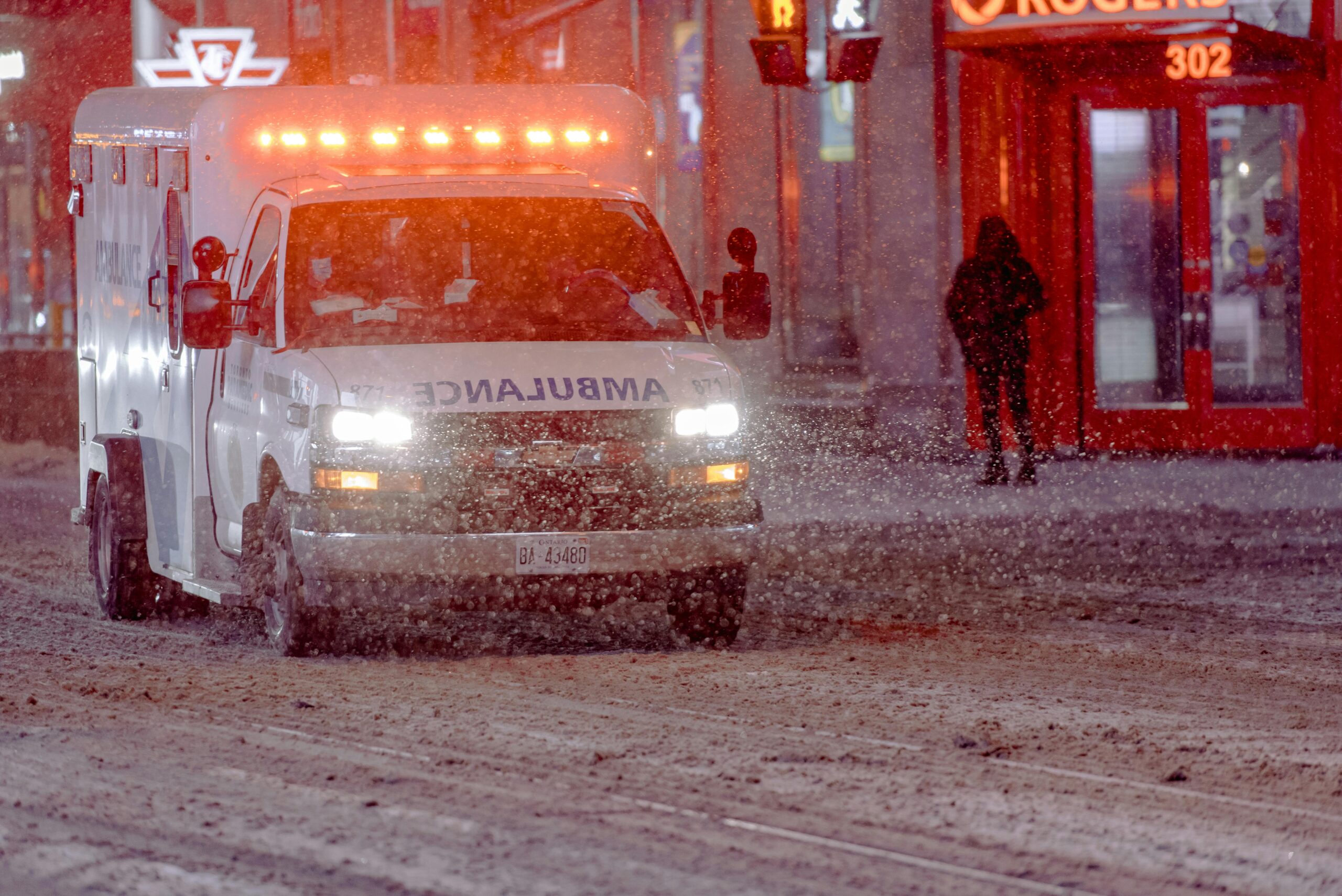 Ambulance driving through snowy roads with its lights on.